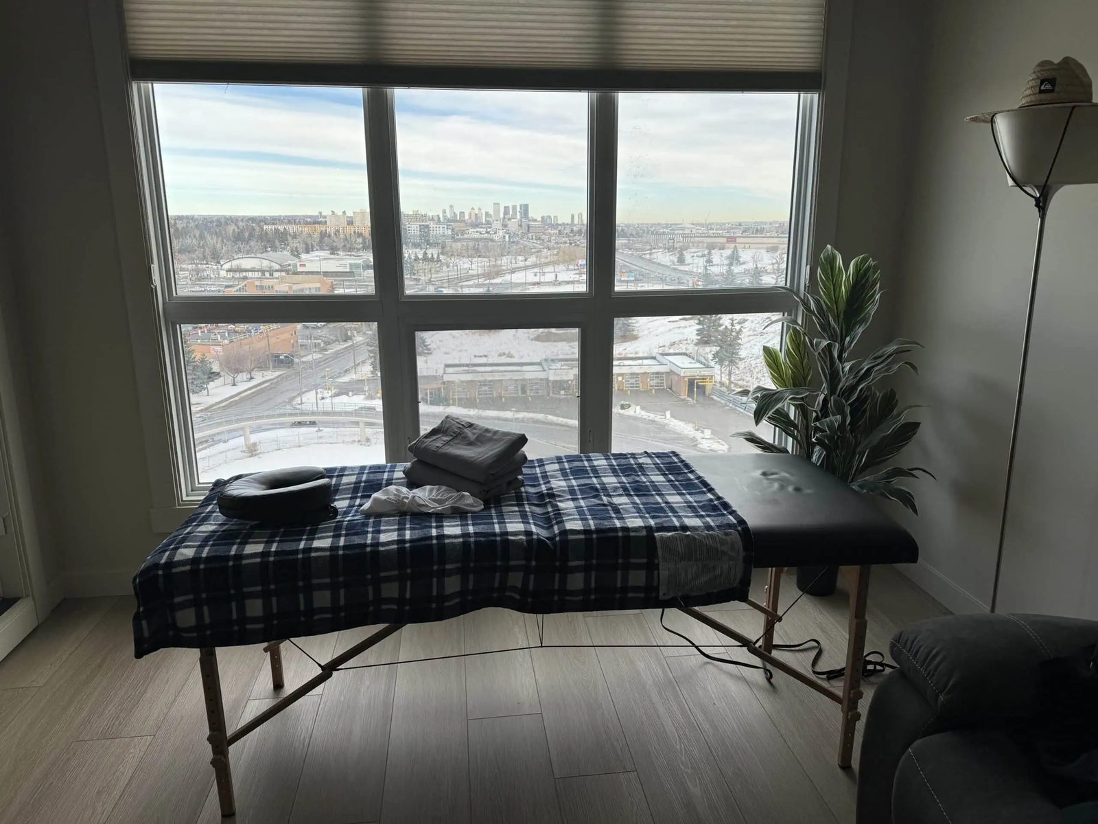 A massage table set up by a bright window overlooking the Calgary skyline
