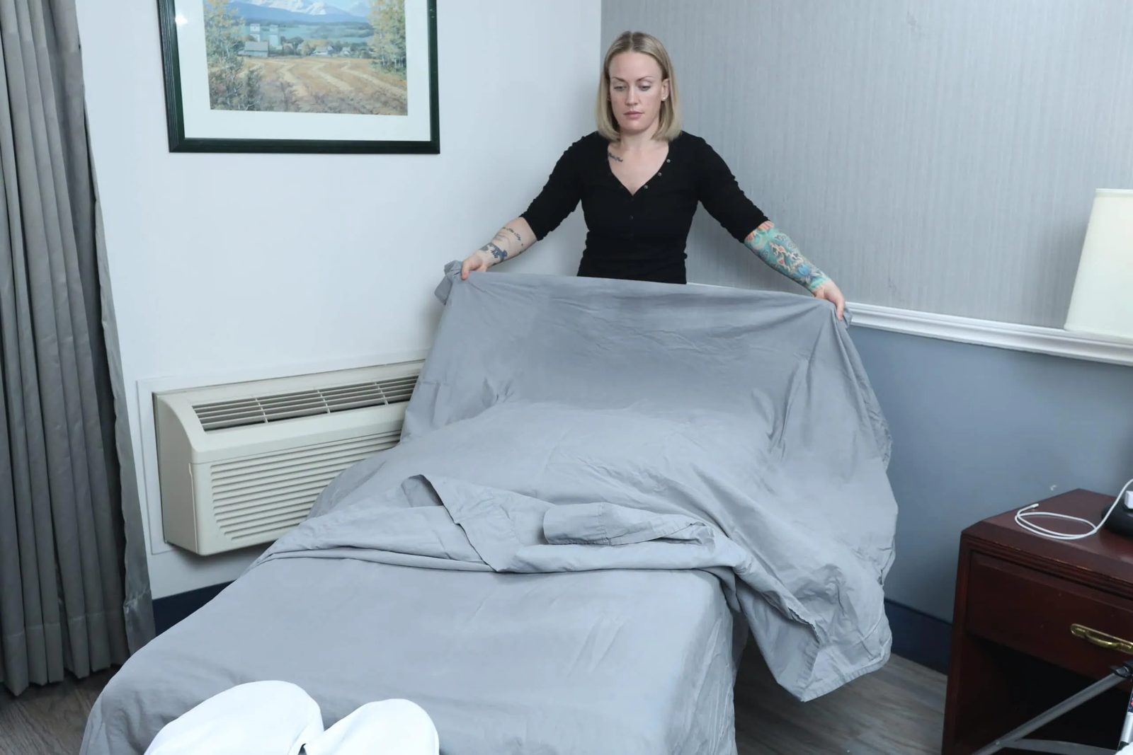 Deidra setting out fresh grey linens on a massage table in a client's room