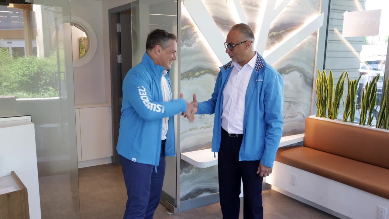 Two men in 123Dentist jackets shake hands in a clinic lobby, the opening shot of Zachary's video reel