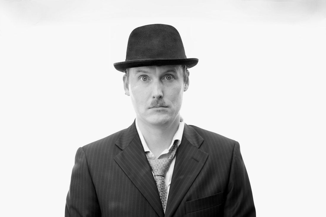 Black and white portrait of Zachary in a bowler hat and pinstripe suit, a nod to Charlie Chaplin