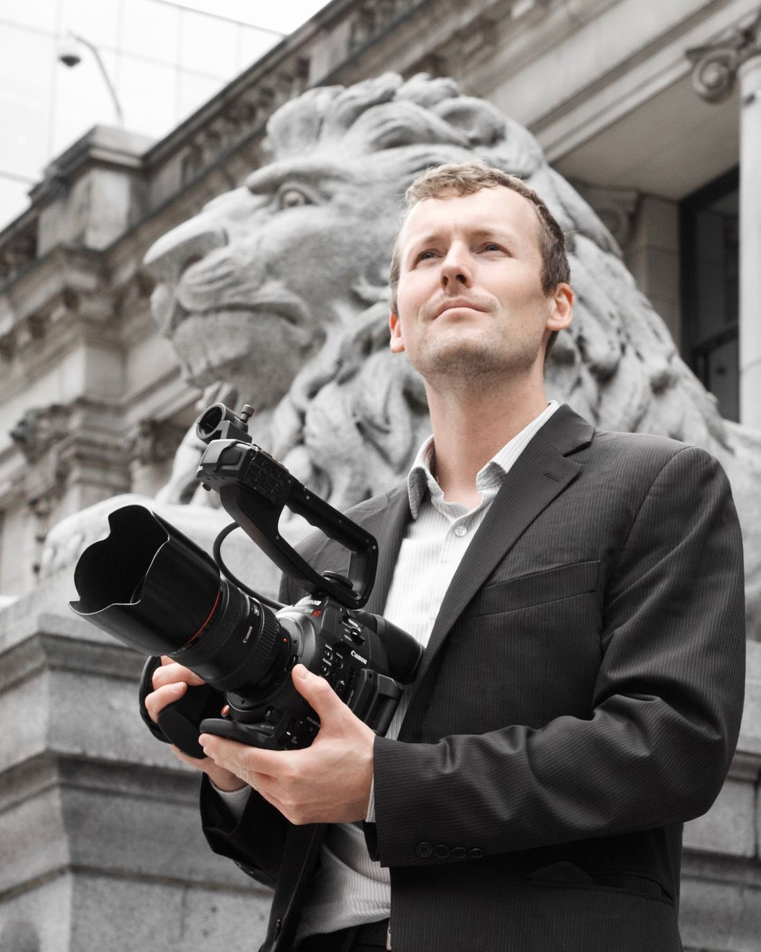 Zachary Tannar holding a cinema camera in front of a stone lion statue