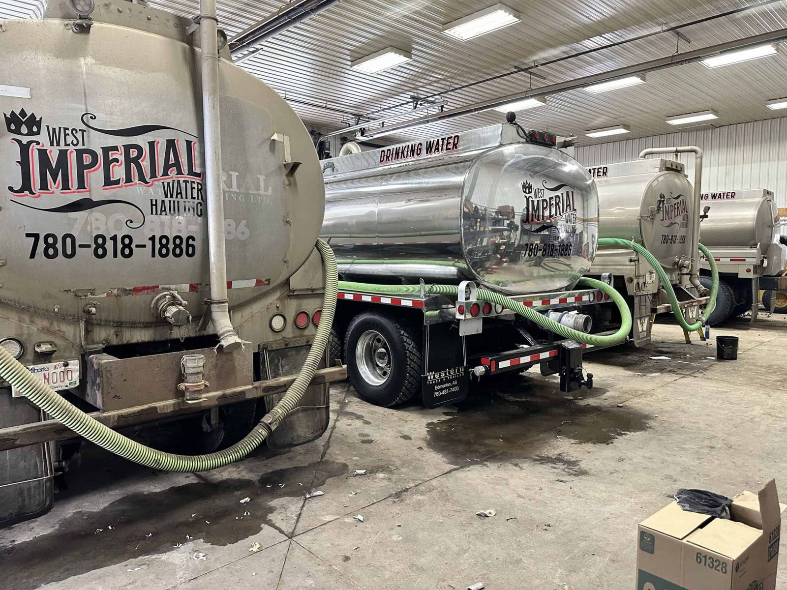 Aluminum water tanks on West Imperial trucks inside the shop, hoses coiled and ready