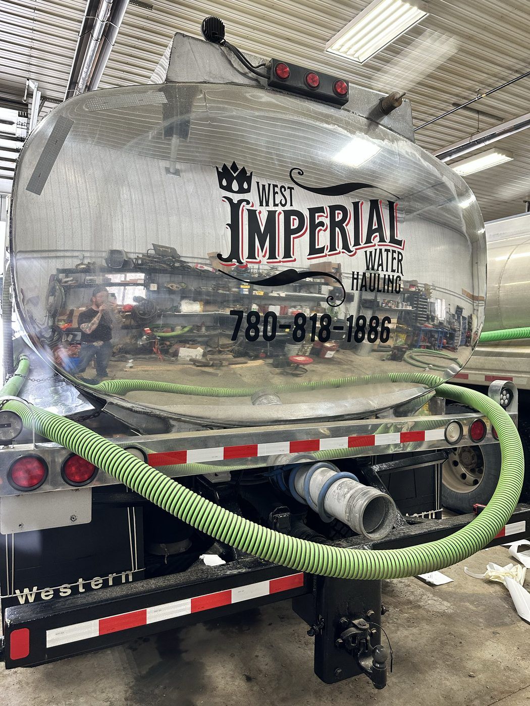 The polished aluminum tank on the back of a West Imperial truck, with the logo and phone number