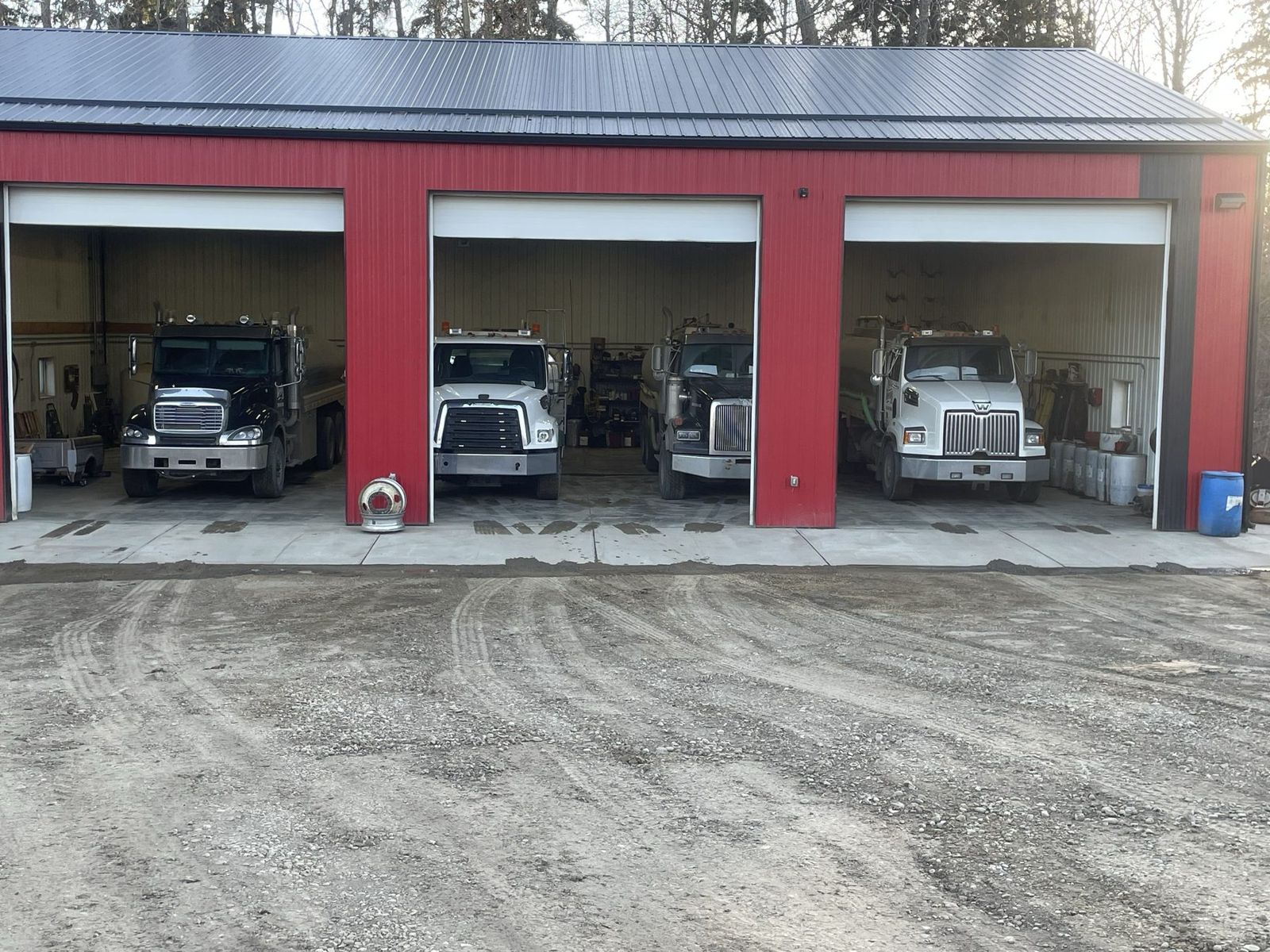 Four West Imperial water trucks in the open bays of the shop