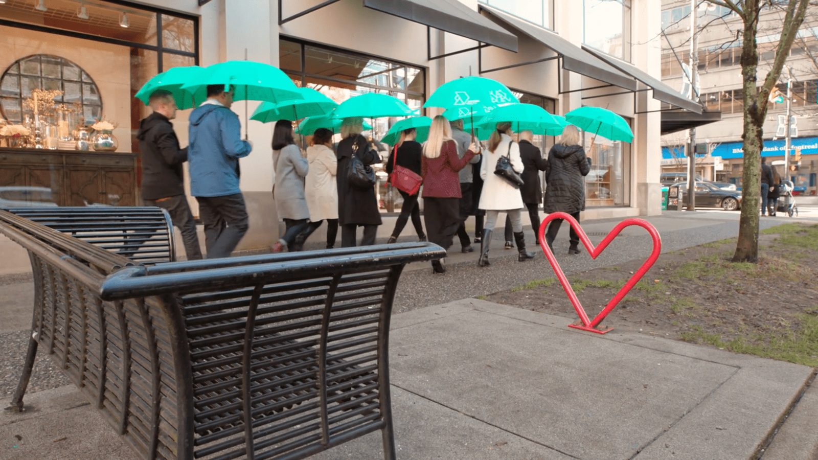People walking under green umbrellas on a city sidewalk, from the Dexter Realty videos