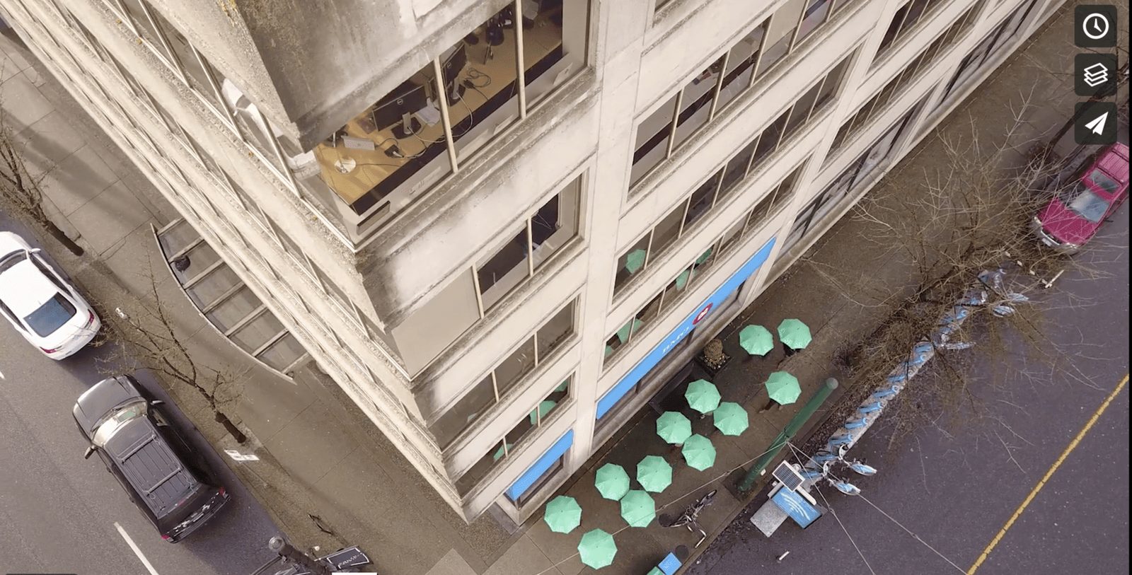 Green umbrellas seen from straight above on a busy street, filmed by drone